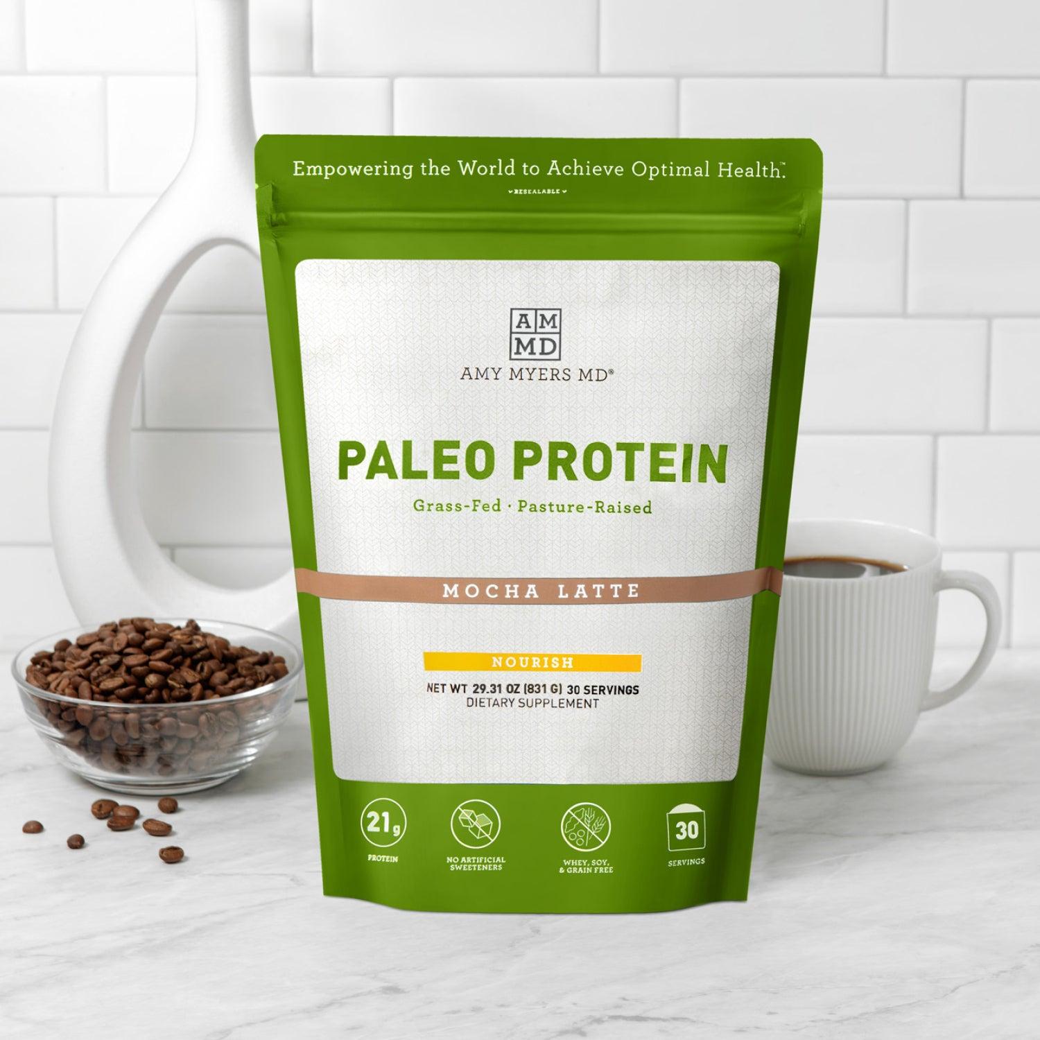 Resealable bag of AMMD Mocha Latte flavored Paleo Protein sitting on a wooden countertop, with white tile background.