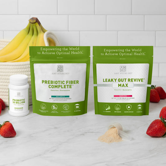 Picture of the Everyday Gut Health Kit on a grey marble counter top in front of a house plant and white wall. The products featured in the kit are presented with the AMMD Prebiotic Fiber Complete next to AMMD Leaky Gut Revive Max, both featured in vibrant Green resealable bags, positioned in back of the white AMMD Probiotic 30 Billion , 30 capsule pill bottle.