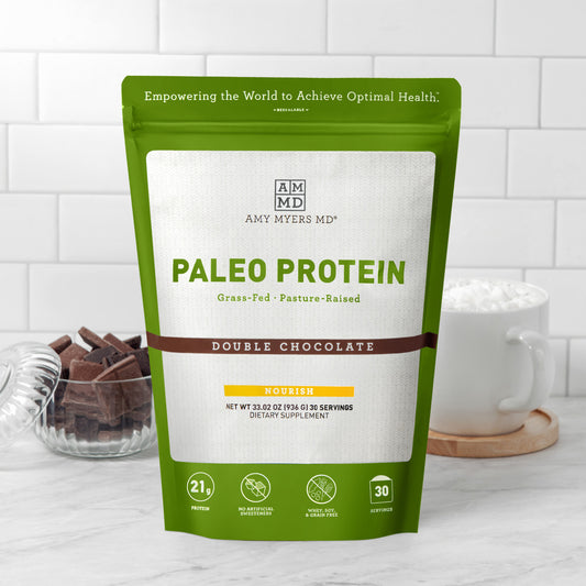 Resealable bag of AMMD Double Chocolate flavored Paleo Protein sitting on a wooden countertop, with white tile background.