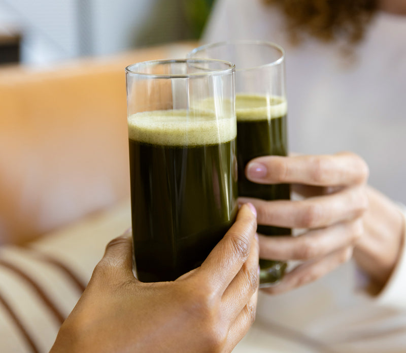 Clinking glasses of Organic Greens green juice - AMMD™ by Amy Myers, MD