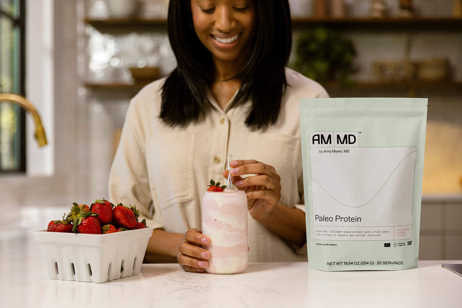 A woman with a smoothie made from strawberries and AMMD™ by Amy Myers, MD Paleo Protein